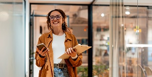 mujer en oficina sonriente con computador en la mano