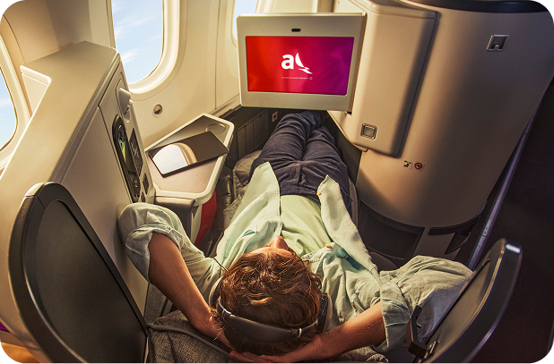 Passager allongé dans un siège Business Class entièrement inclinable avec écran de divertissement